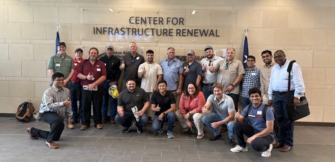 A group of people posed in front of a business sign for the Center for Infrastructure Renewal. 